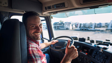 portrait-truck-driver-sitting-his-truck-holding-thumbs-up